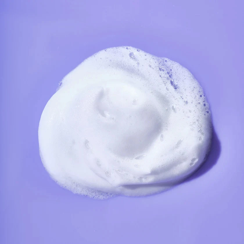 Photo of a dollop of the foaming cleanser on a purple background