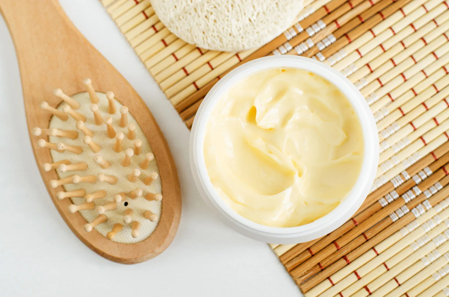 A white jar of nourishing body butter on a bamboo mat