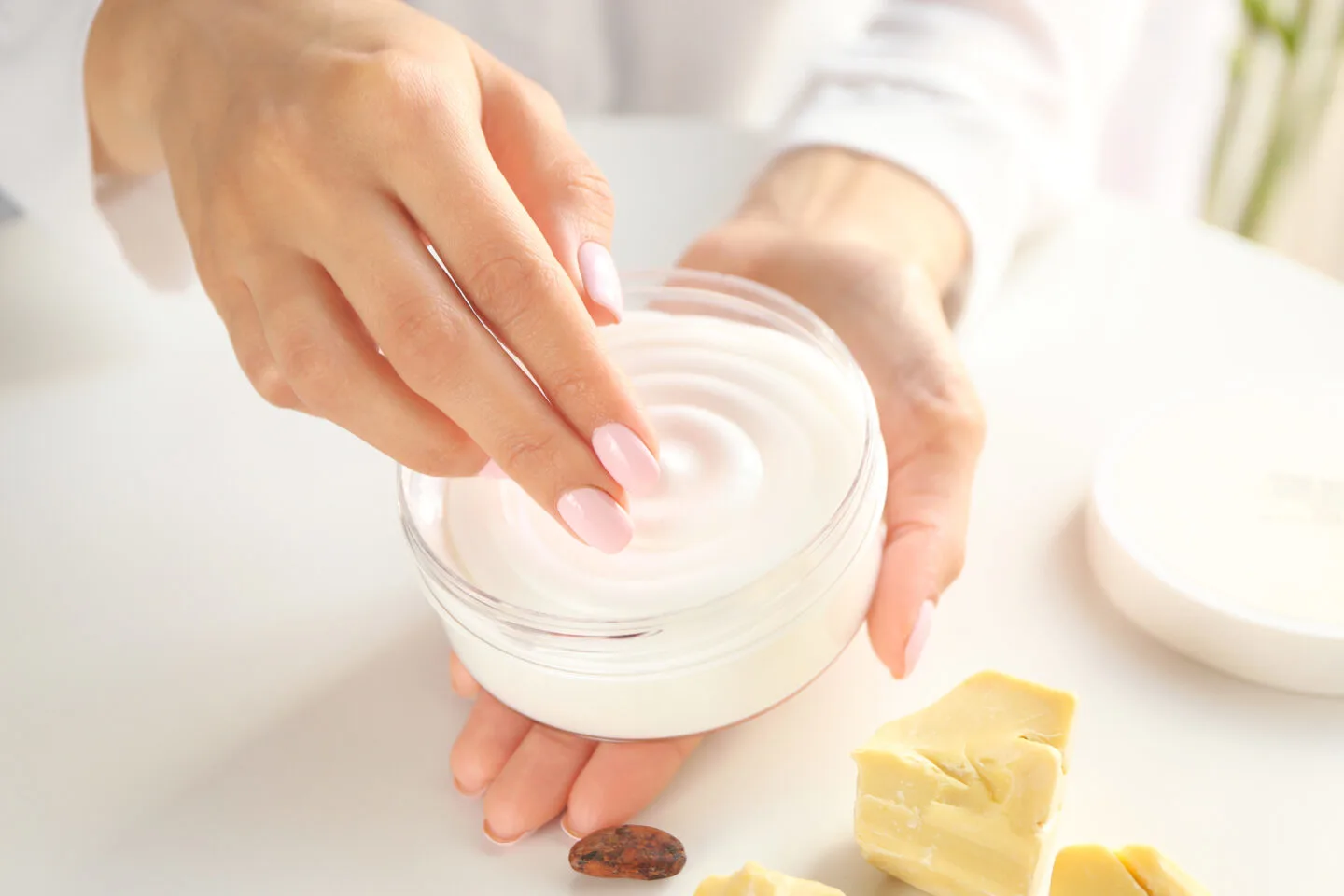 Jar of body butter being scooped out with fingers