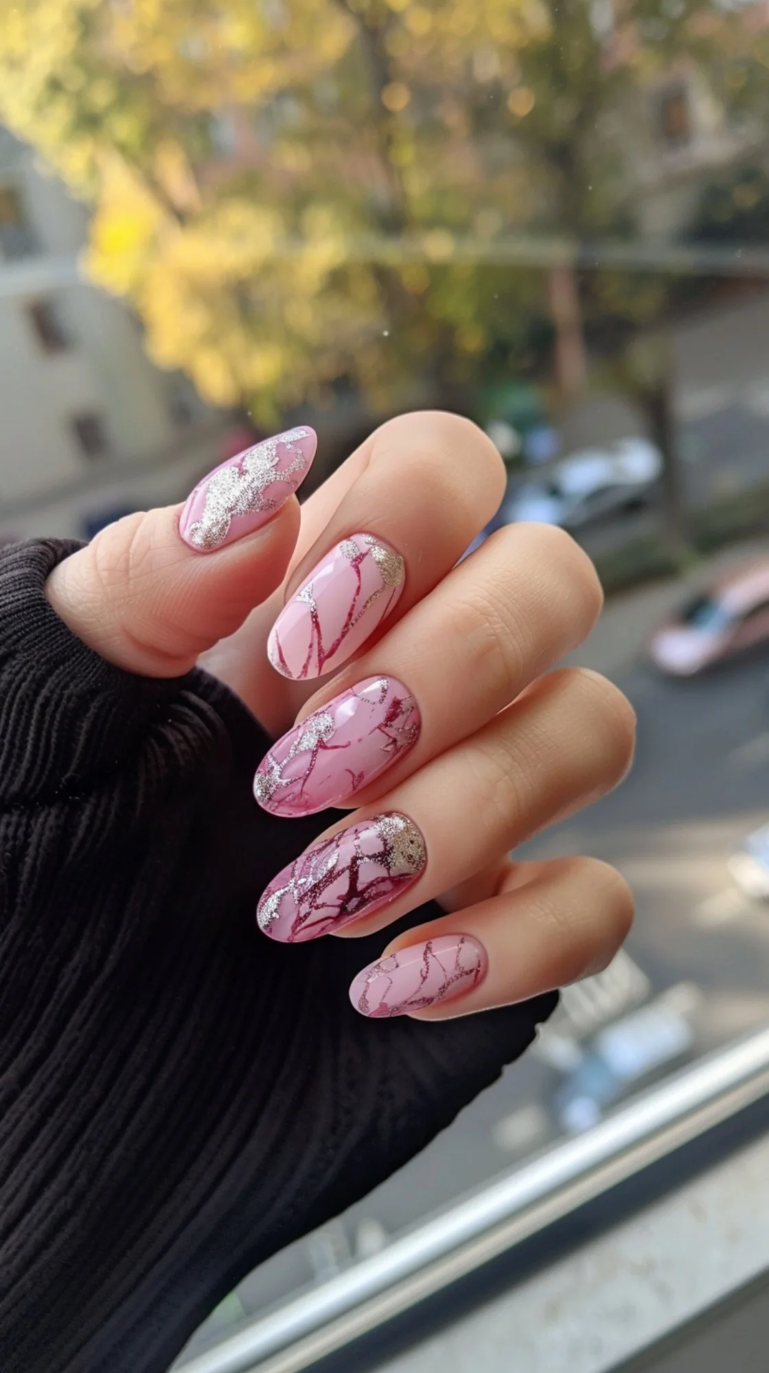 These nails are adorned with a combination of light pink and bold marbled patterns, highlighted with metallic glitter. The dynamic design is eye-catching and stylish, perfect for making a statement.