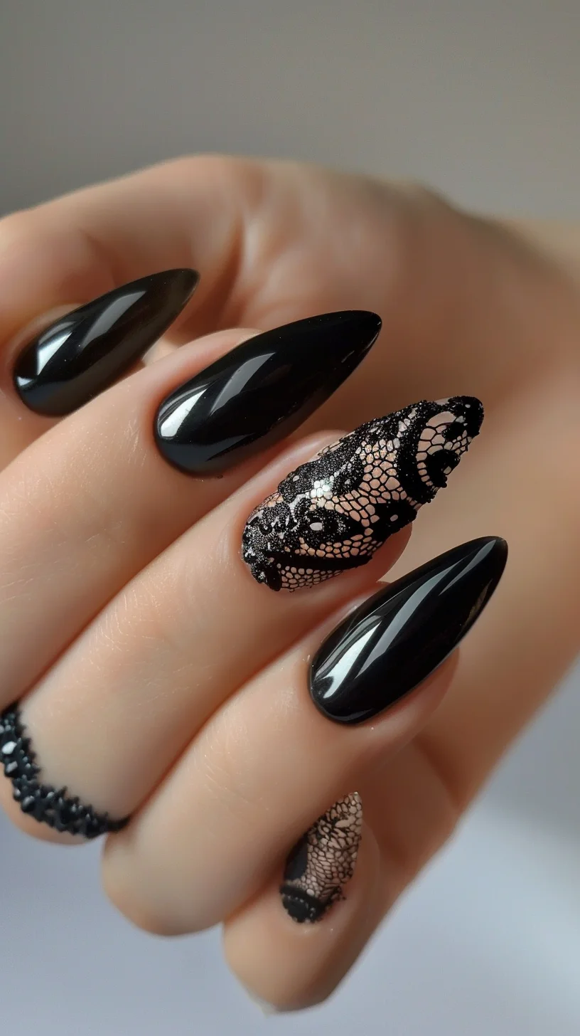 Glossy black nails are accented with a lace design on the ring finger, featuring a nude base with black floral lace patterns. The nails are stiletto-shaped, giving a sleek and modern look that combines elegance with a touch of edginess.