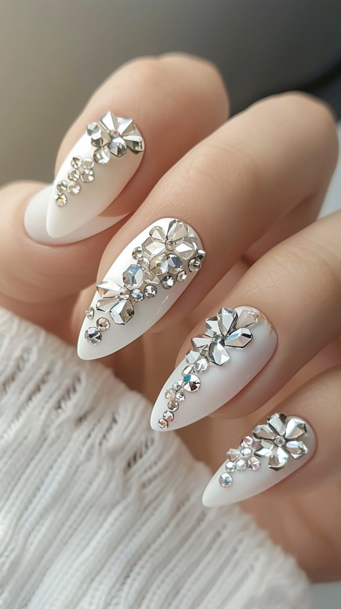 Featuring a white base with large, statement crystals, these nails create a bold and luxurious look. The crystals are arranged in floral patterns, adding a touch of elegance and sophistication. This design is perfect for making a strong and stylish impression.