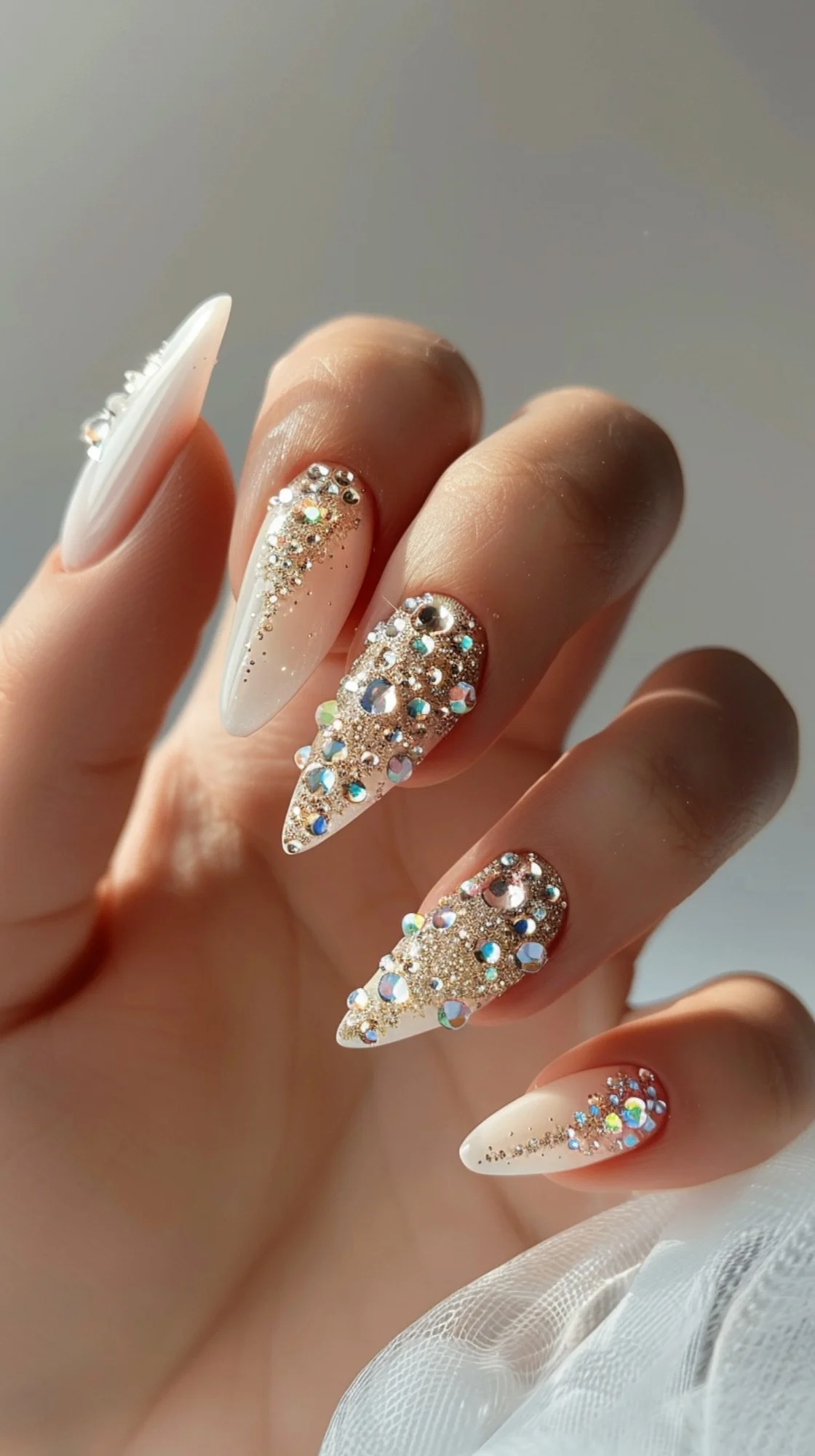 These nails feature a white base with a gradient of golden glitter and crystals. The crystals are arranged in a cascading pattern, starting at the cuticle and gradually spreading out towards the tips. This look is perfect for adding a touch of sparkle and glamour to your style.