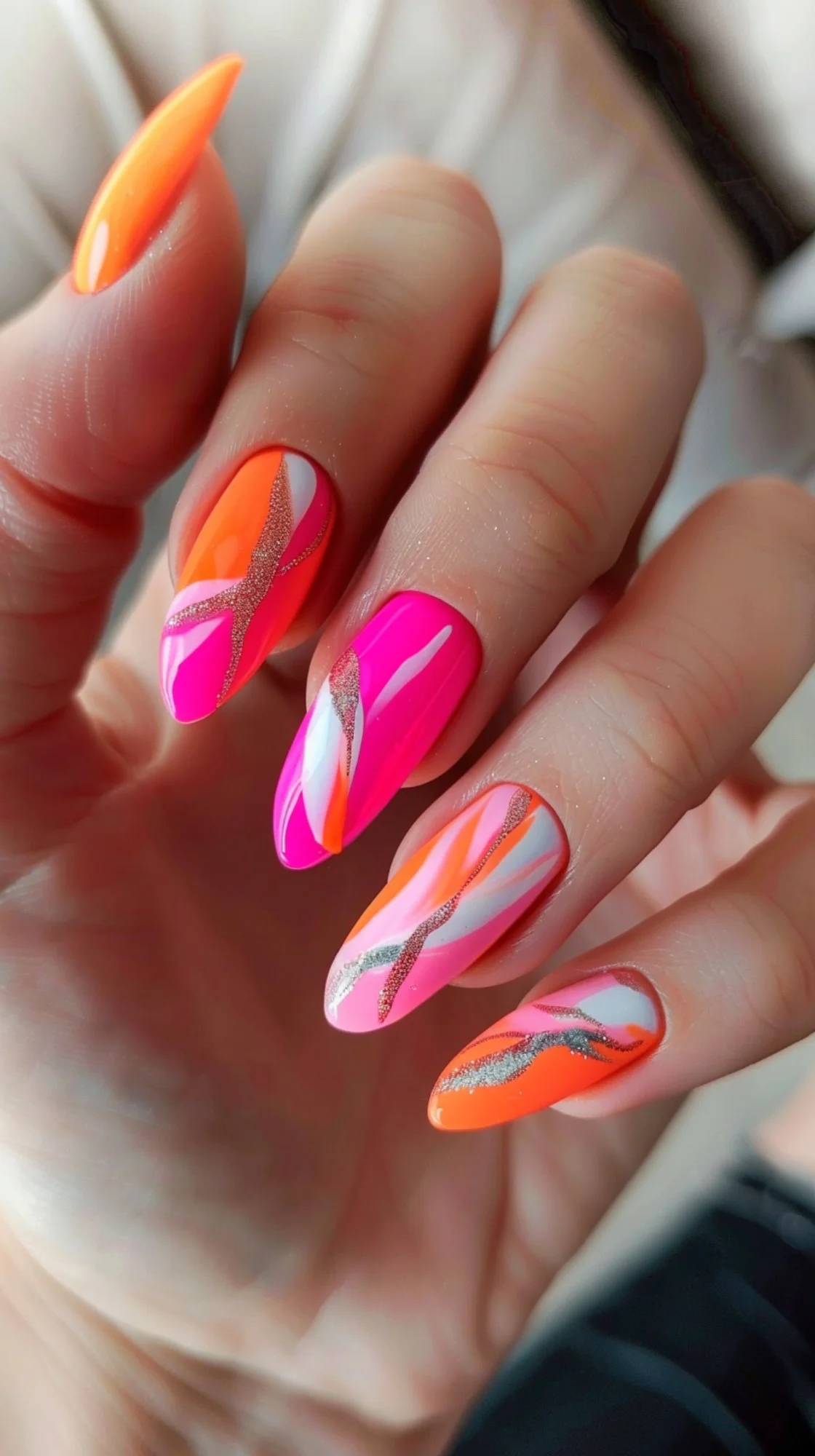 Pink and orange nails are adorned with swirling patterns and glitter accents. The dynamic design adds a sense of movement and energy, perfect for a lively summer vibe.