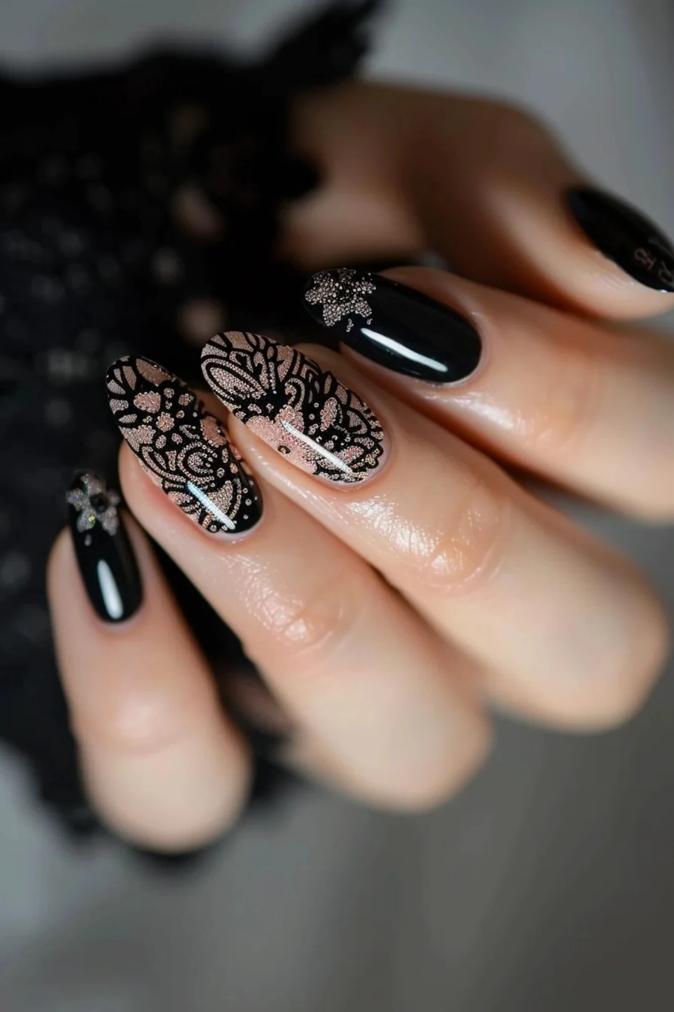Combining glossy black polish with intricate black lace designs, these almond-shaped nails feature floral and geometric motifs. The lace is detailed with subtle glitter accents, adding a touch of sparkle to the sophisticated and elegant design.
