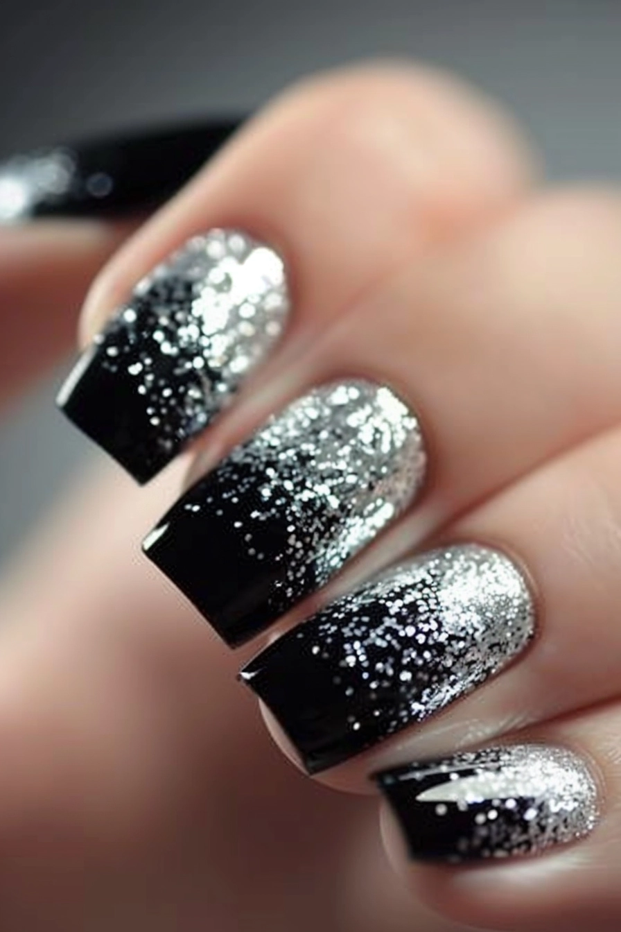 Square-shaped nails with a black base, heavily coated with silver glitter at the tips, creating a striking and bold contrast.