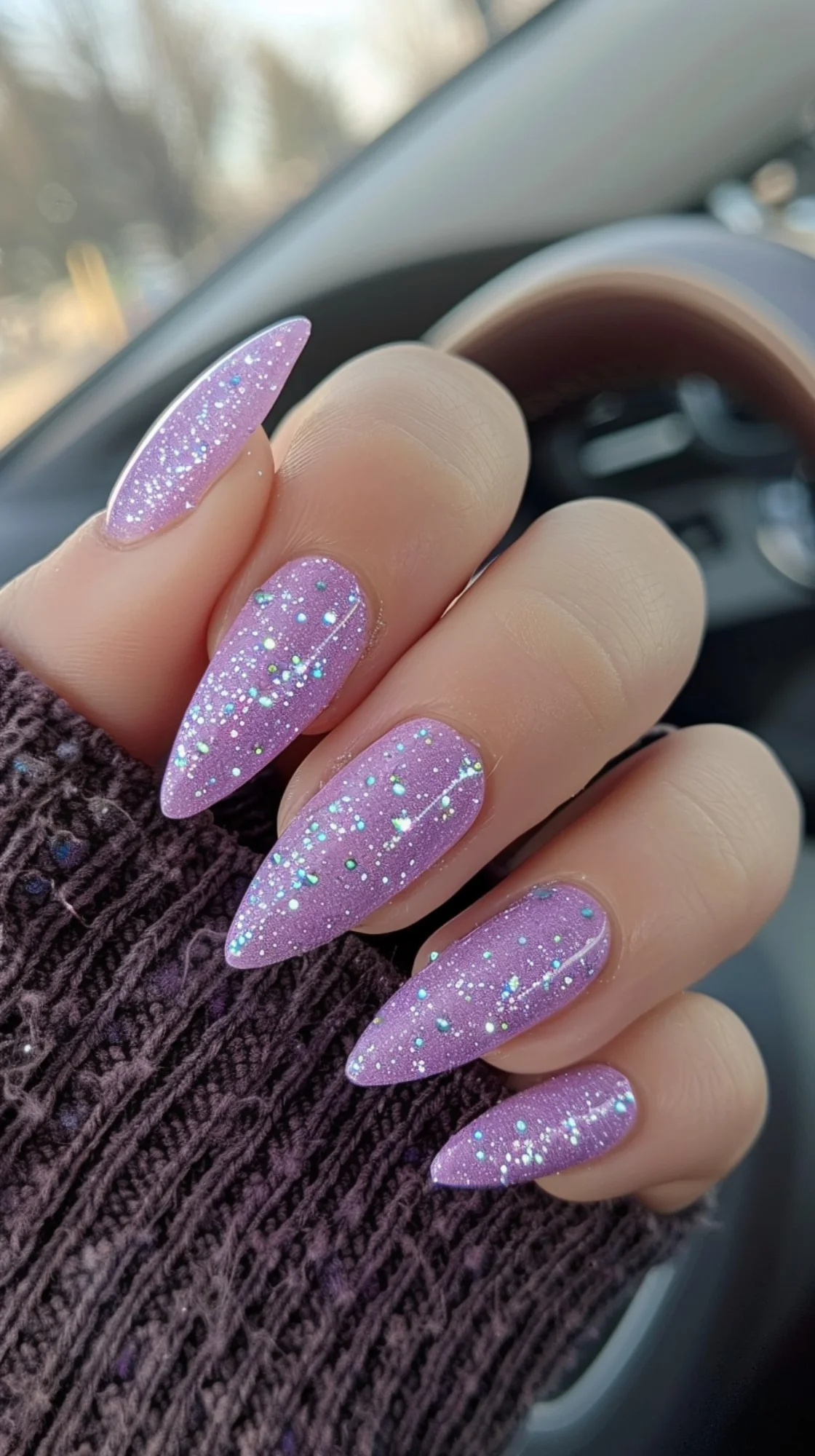 This nail design features a light purple base with a subtle dusting of fine glitter. The almond shape of the nails complements the understated elegance of the sparkle, making them perfect for both casual and formal settings.
